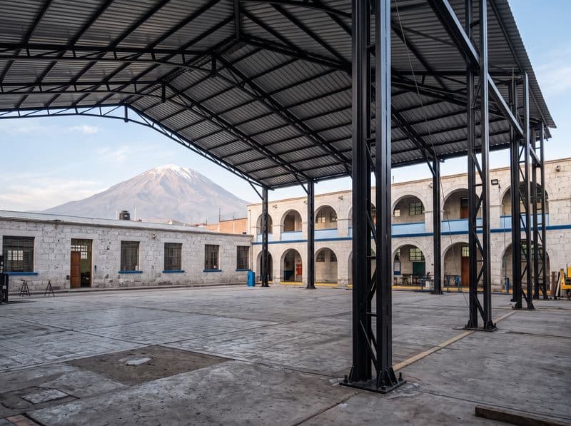 Cobertura metálica de dos aguas recién instalada sobre el patio de un colegio